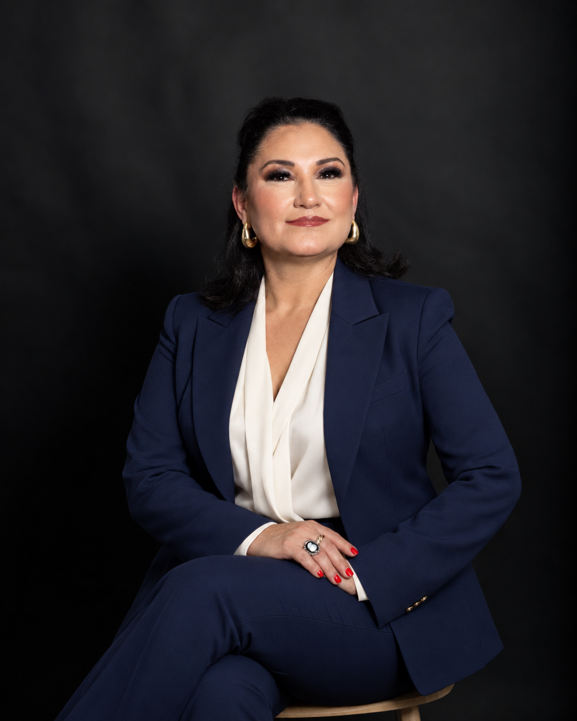 Retrato de la Dra. Gloria Ana Araujo Linares sentada, con traje azul marino y blusa blanca.